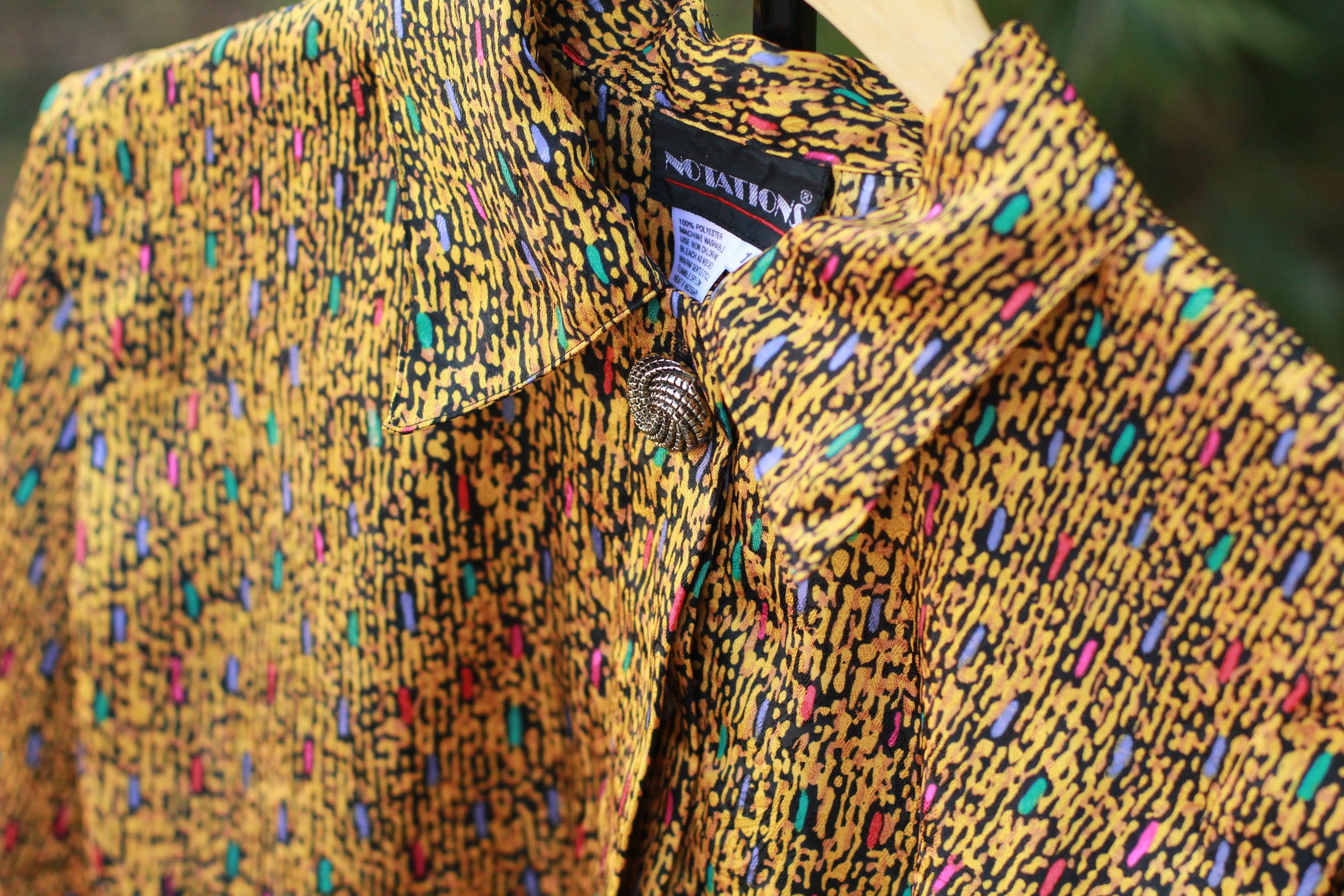 Detail of collar and unique patterned button on vintage abstract print top.