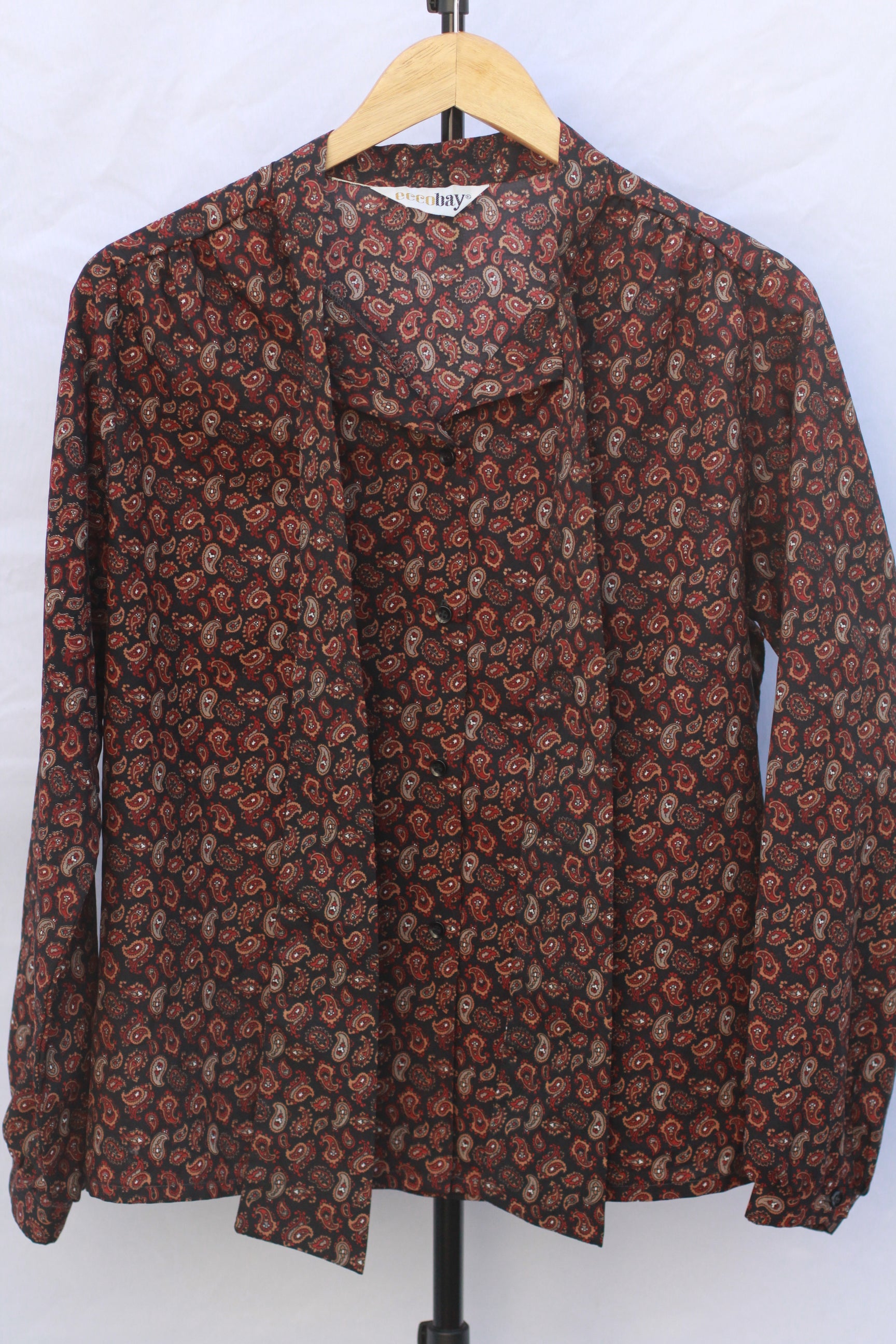 Vintage black paisley pussy bow blouse from the 1970s on hanger