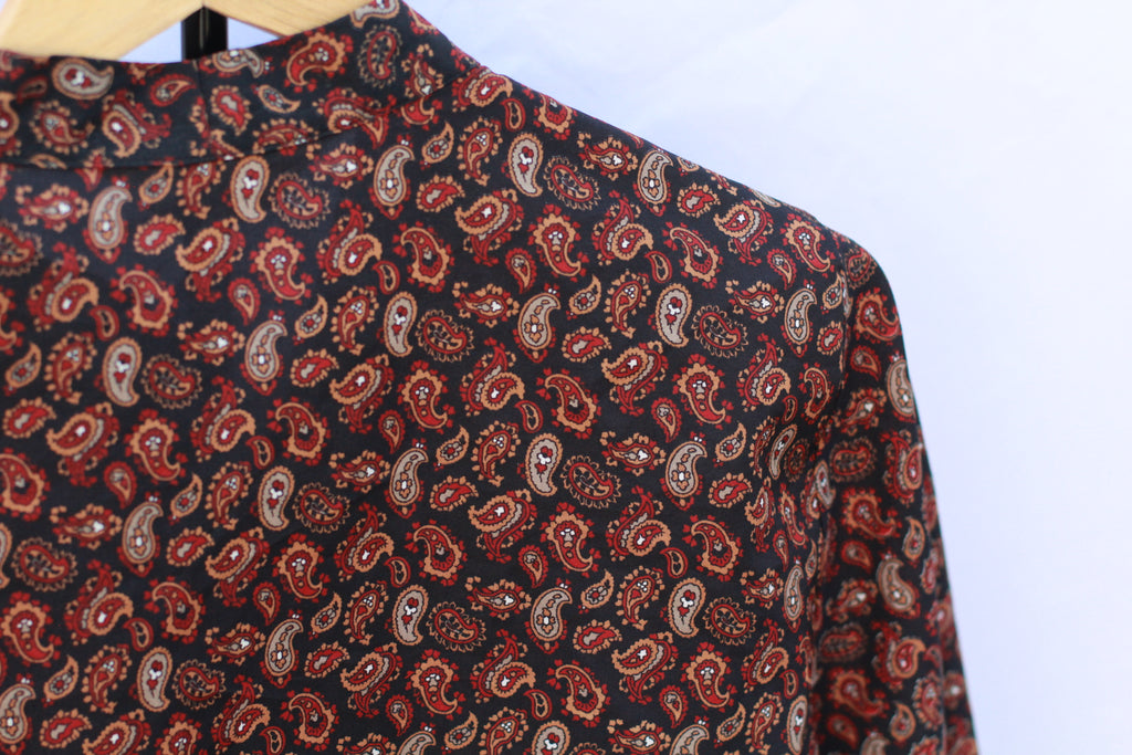 Close-up of 70s paisley print in black, orange, red, and gray