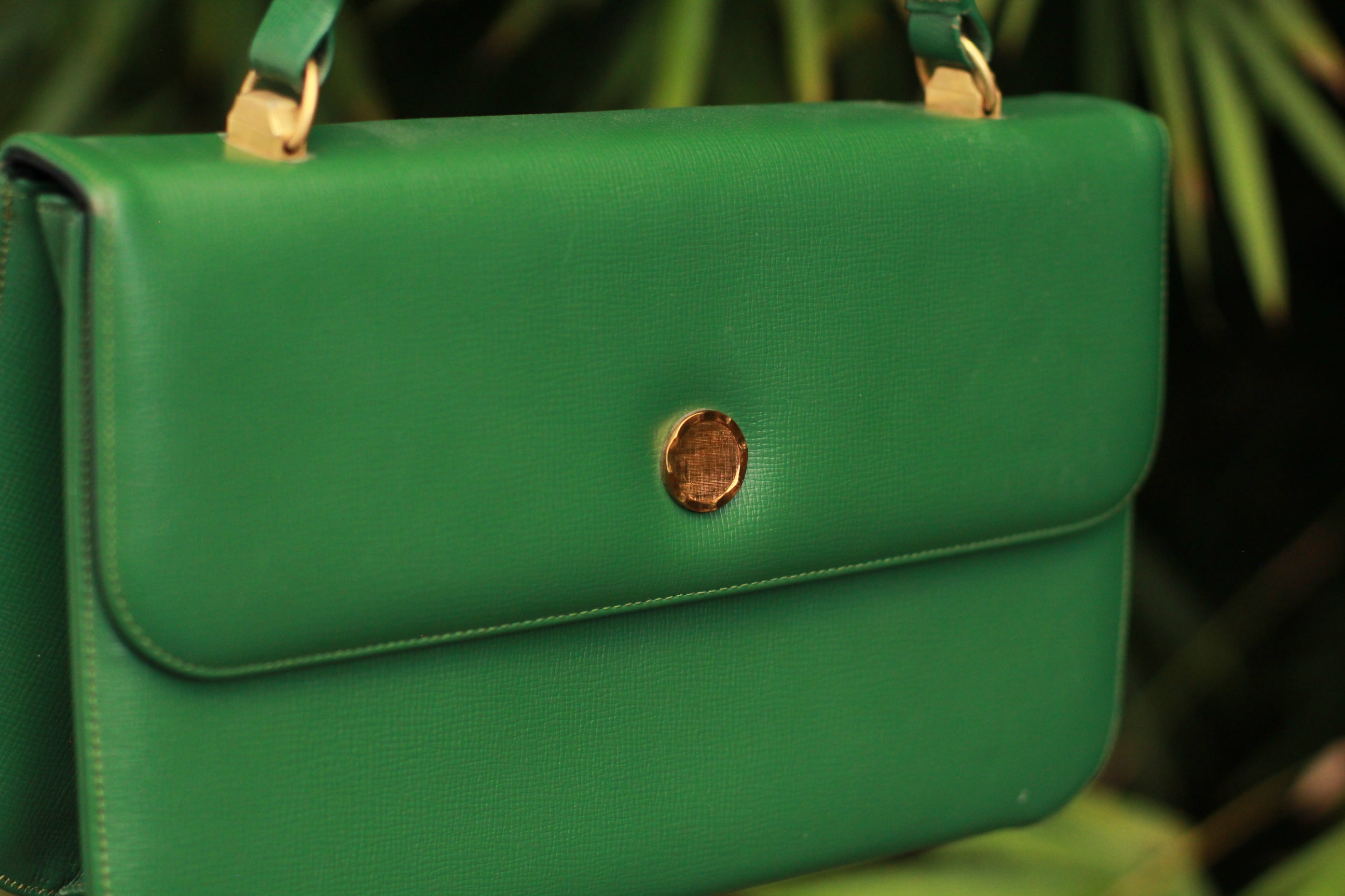 Side view of structured top handle green leather bag