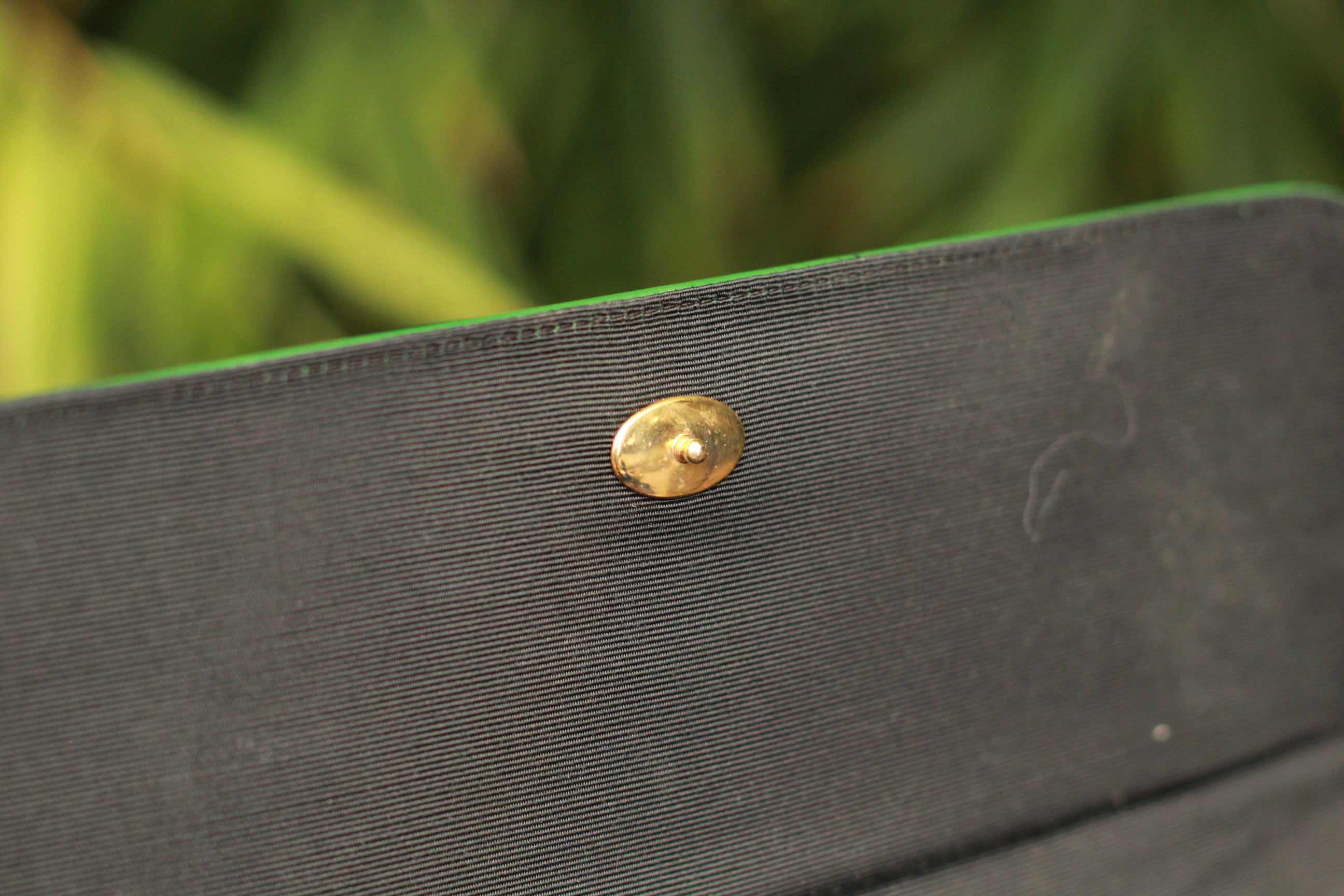 View of vintage 1990s green leather handbag with gold button clasp
