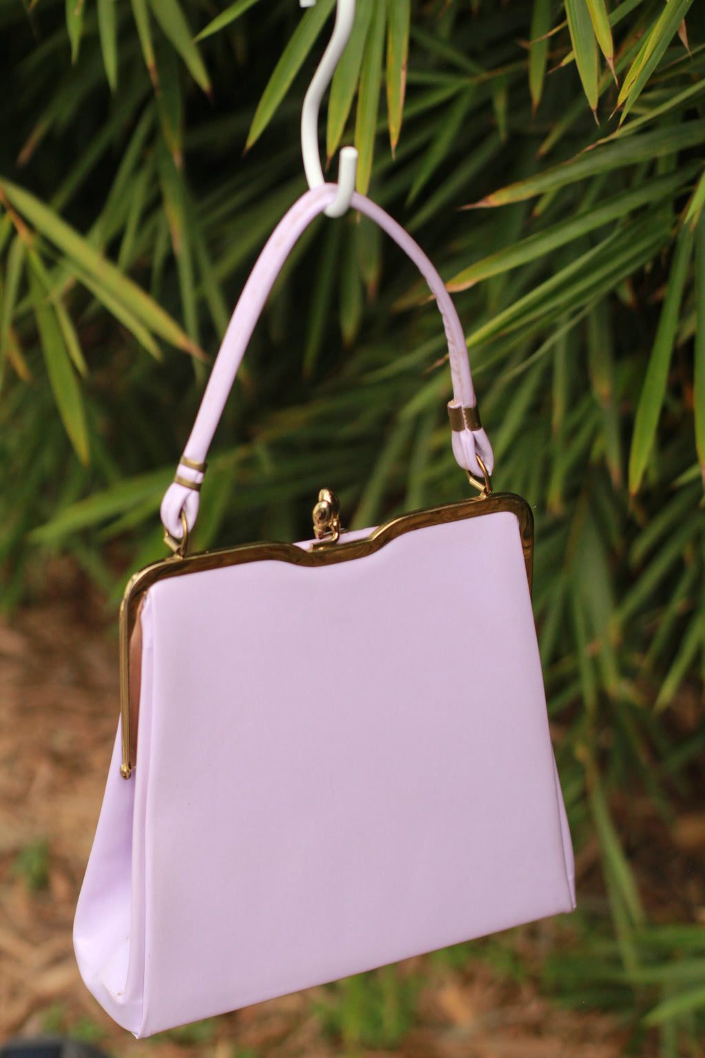 Front view of vintage lavender kiss-lock handbag with gold-tone hardware