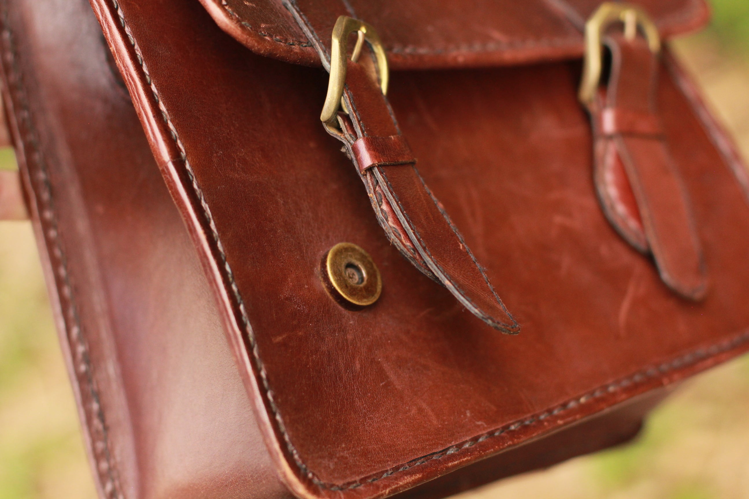 Brass hardware magnetic closures on leather messenger bag