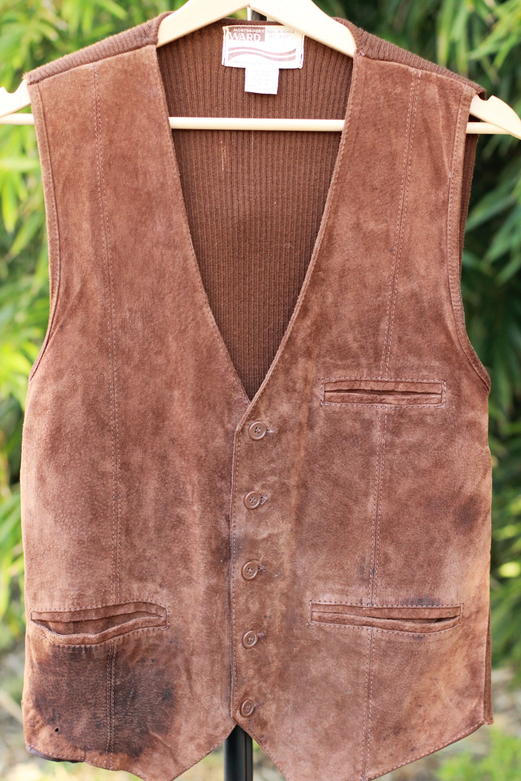 Front view of brown suede vest with button closure and pockets