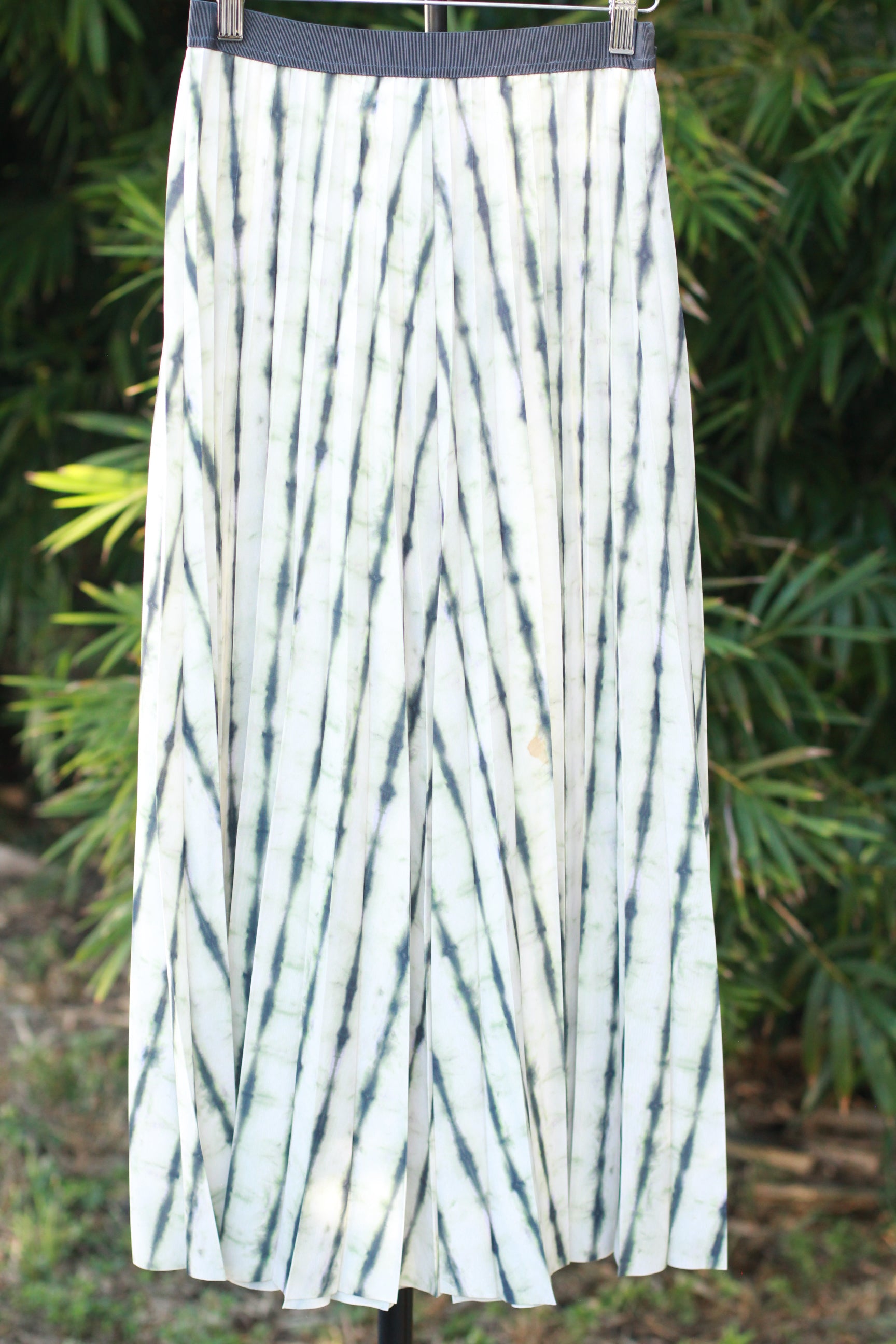 Front view on hanger — pleated white and green tie-dye midi skirt