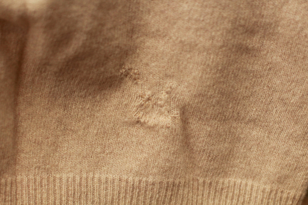 Close-up of knit texture and repaired stitching on vintage sweater vest