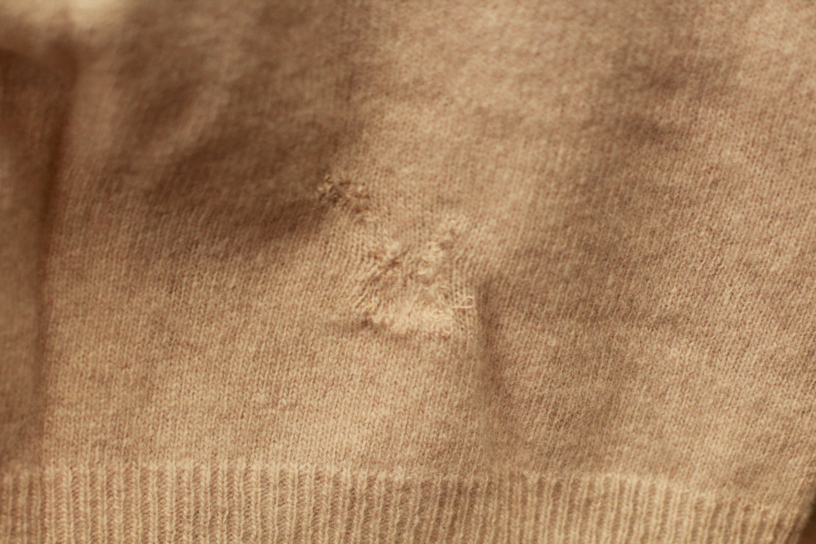 Close-up of knit texture and repaired stitching on vintage sweater vest