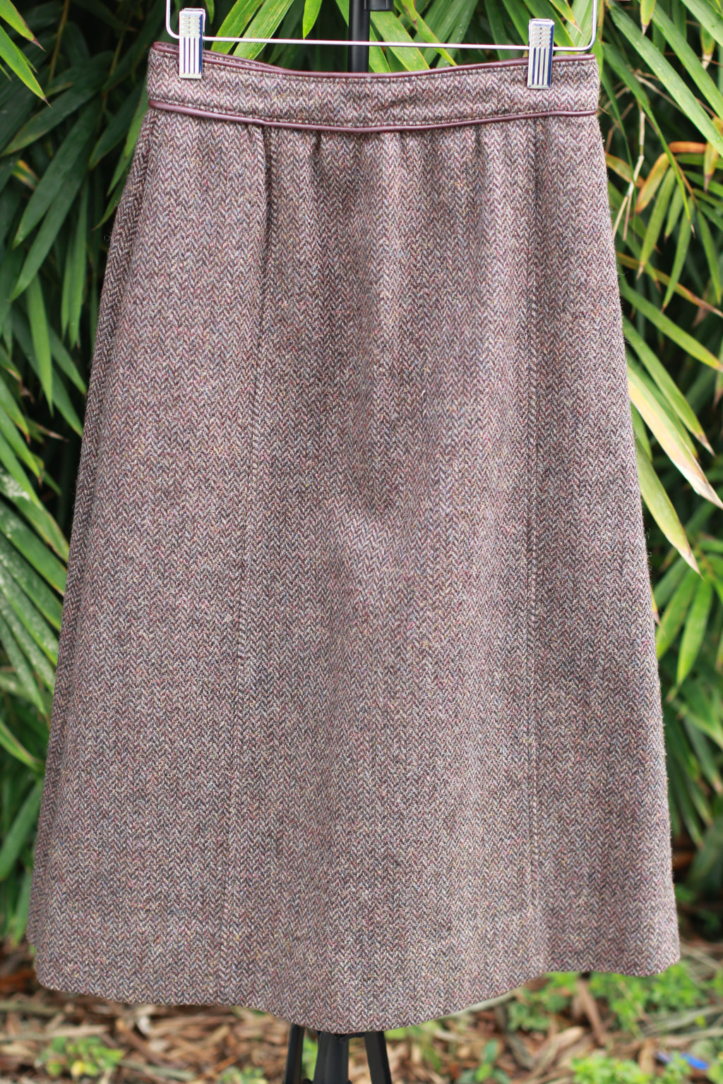 Front view of 1970s The Villager brown tweed A-line skirt with maroon leather trim