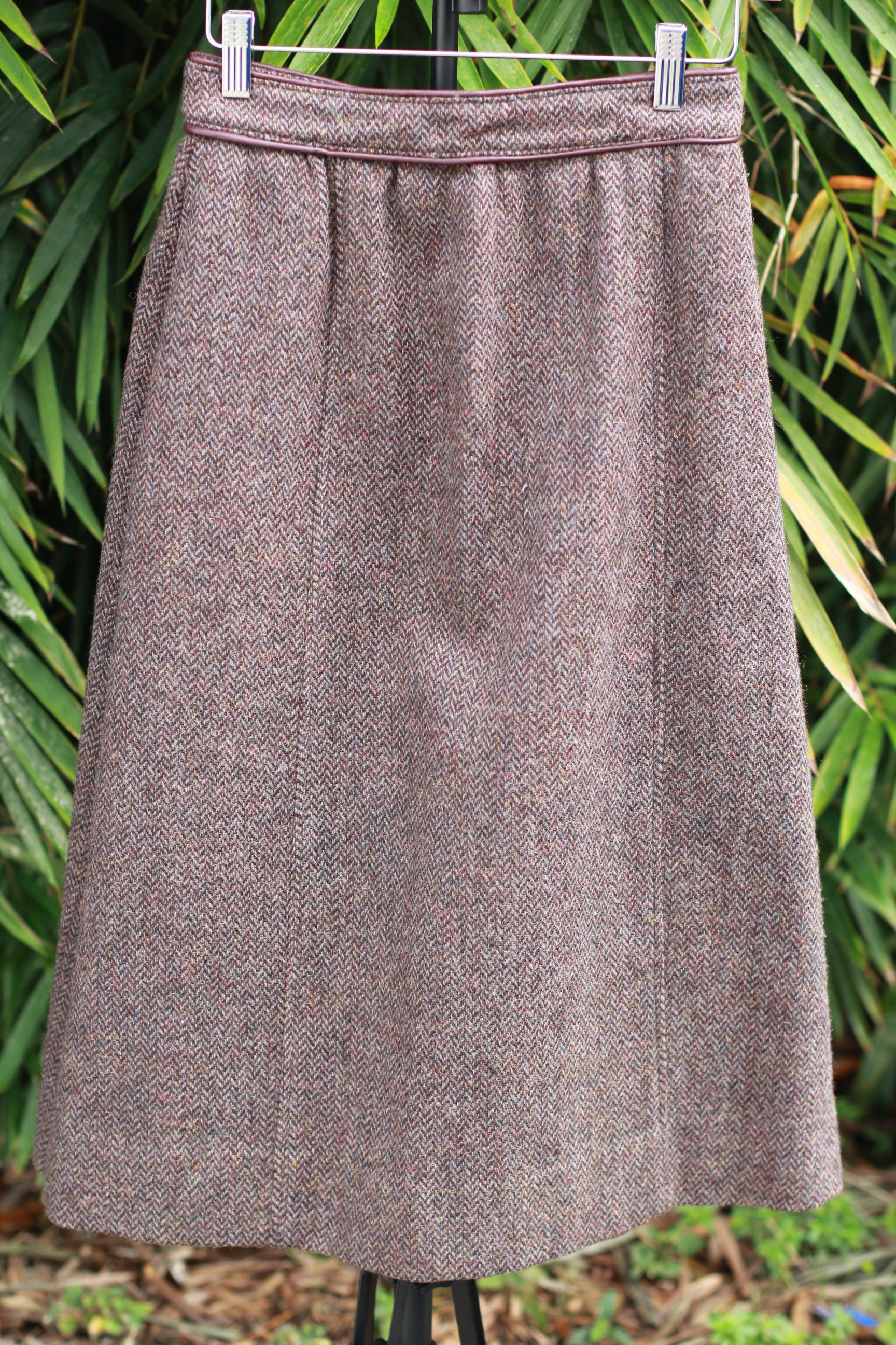 Front view of 1970s The Villager brown tweed A-line skirt with maroon leather trim