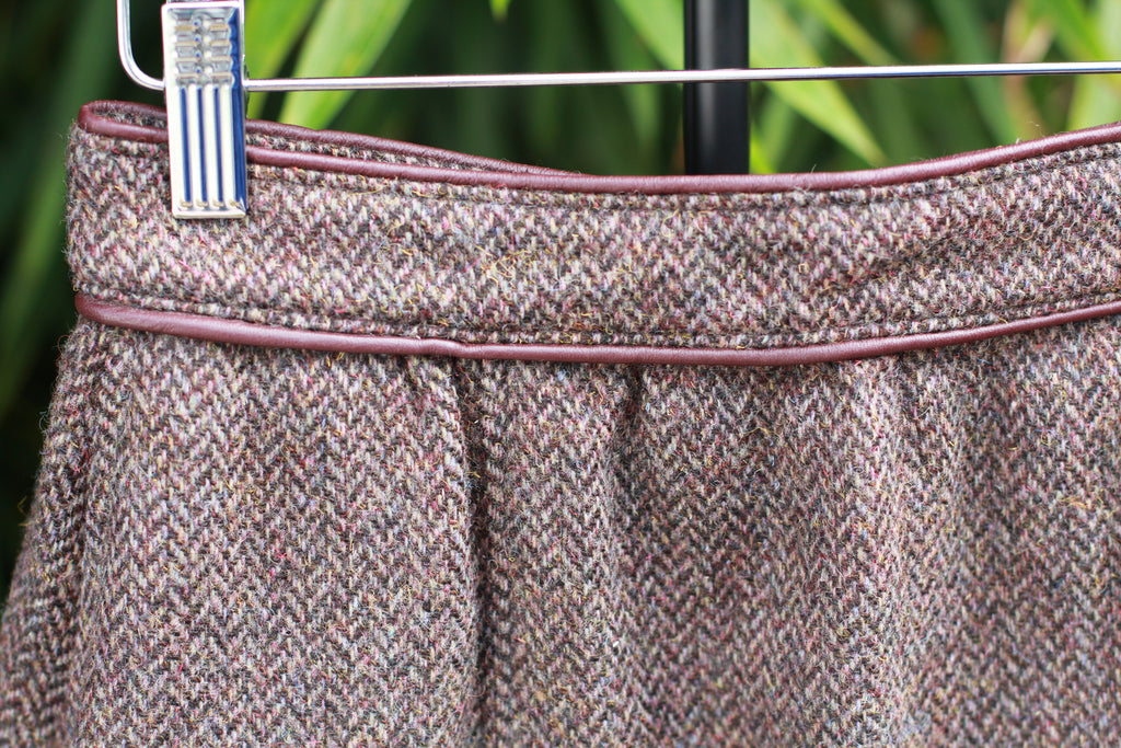 Close-up of herringbone tweed wool fabric and leather waistband detail