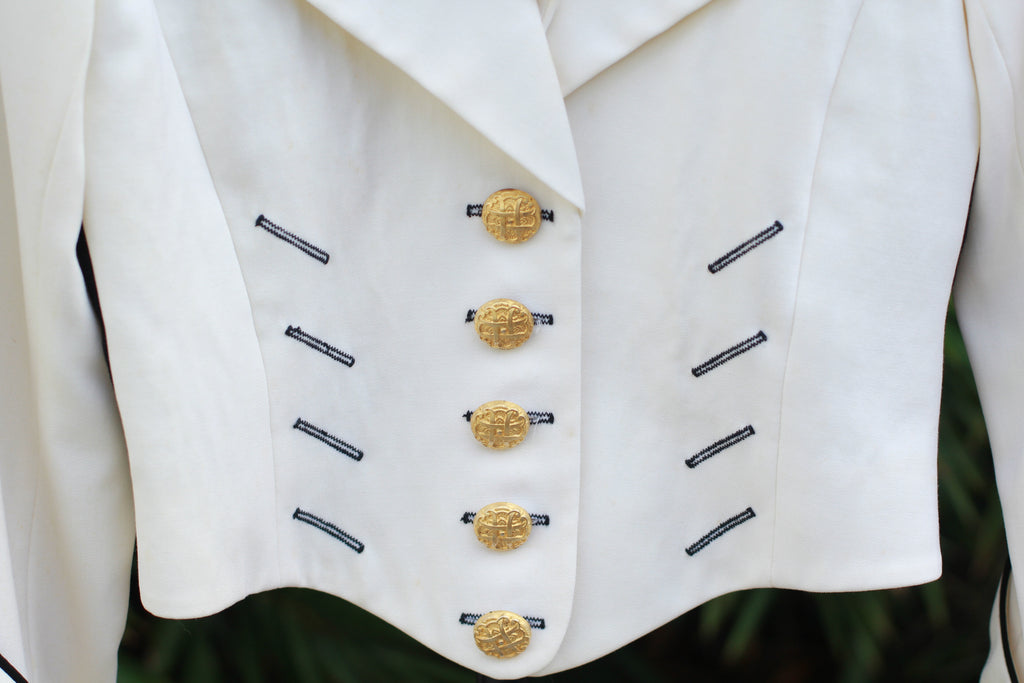 Close-up of gold buttons and black trim on vintage CACHÉ jacket