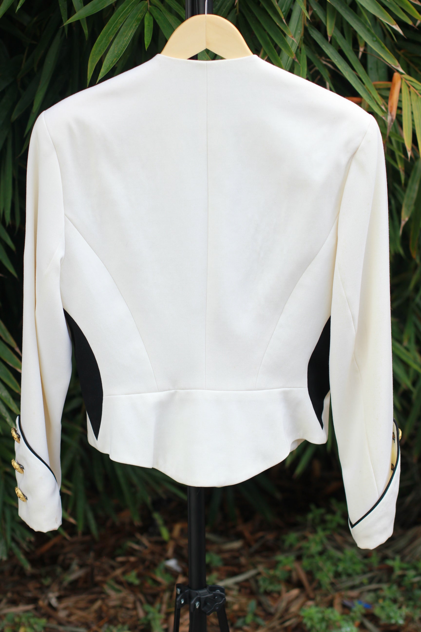 Back view of cream cropped military-style jacket with padded shoulders